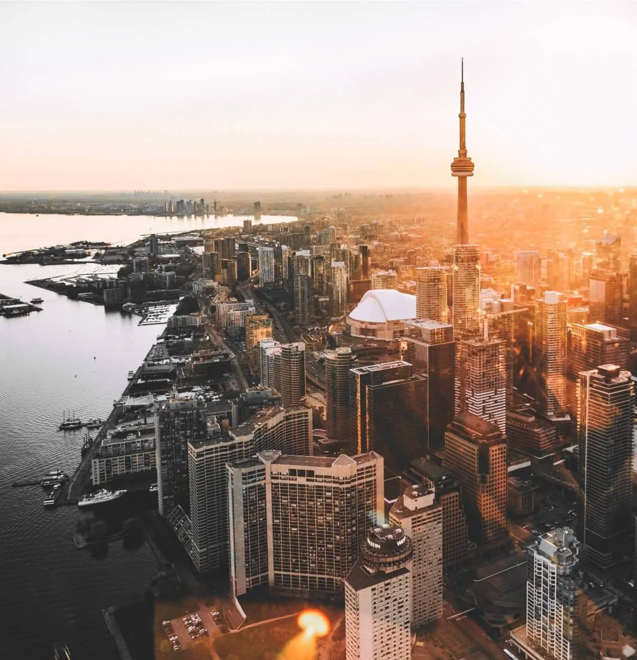 A city skyline from the air at golden hour, the lake and harbour running to the horizon.